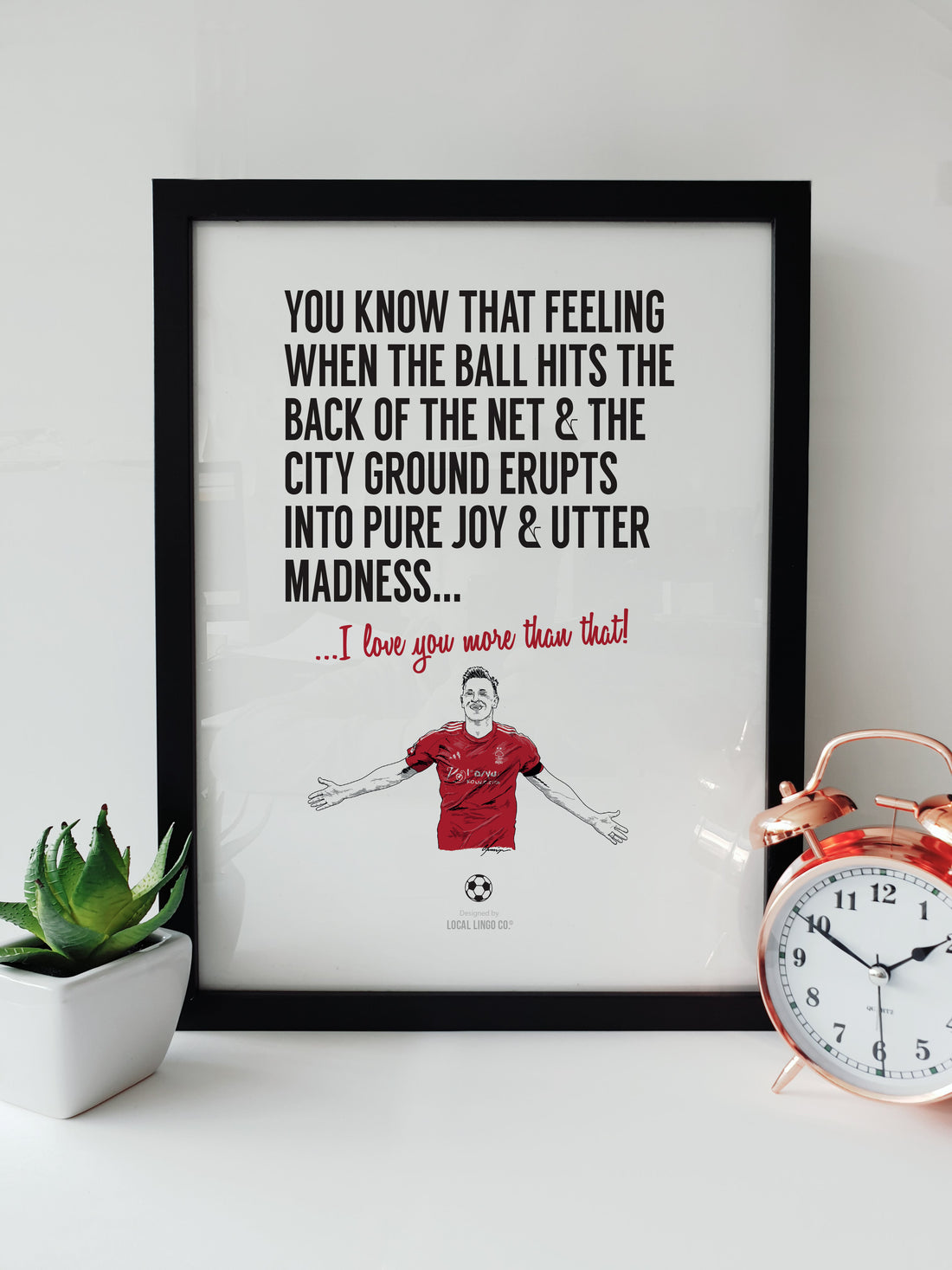 Hand-drawn illustration of Nottingham Forest striker Chris Wood celebrating a goal at the City Ground, designed by Local Lingo. The artwork features bold text that reads: "You know that feeling when the ball hits the back of the net & the City Ground erupts into pure joy & utter madness... I love you more than that!" Displayed in a black frame.